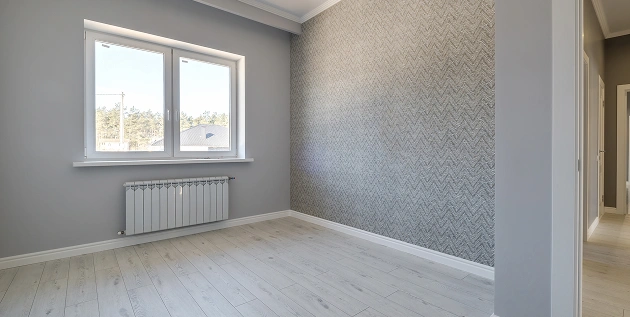 Een lege kamer in renovatie met betonnen plafond, gereedschap en grote ramen.