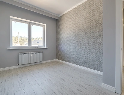Een lege kamer in renovatie met betonnen plafond, gereedschap en grote ramen.
